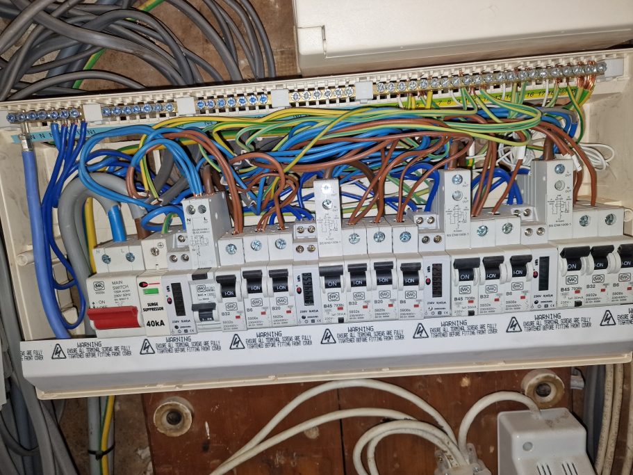 Old single‑phase office consumer unit with poor identification, no SPD protection, and loose meter connections